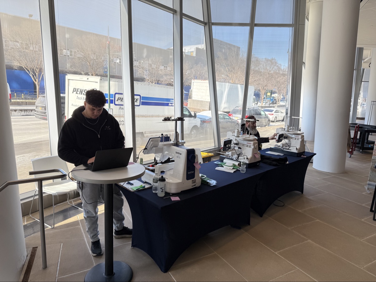 Live embroidery machines set up on a draped table at an event venue